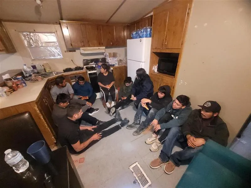 In a photo shared on Laredo Border Patrol’s social media account, 10 individuals — most with their faces obstructed — can be seen sitting on the kitchen floor inside the home. 