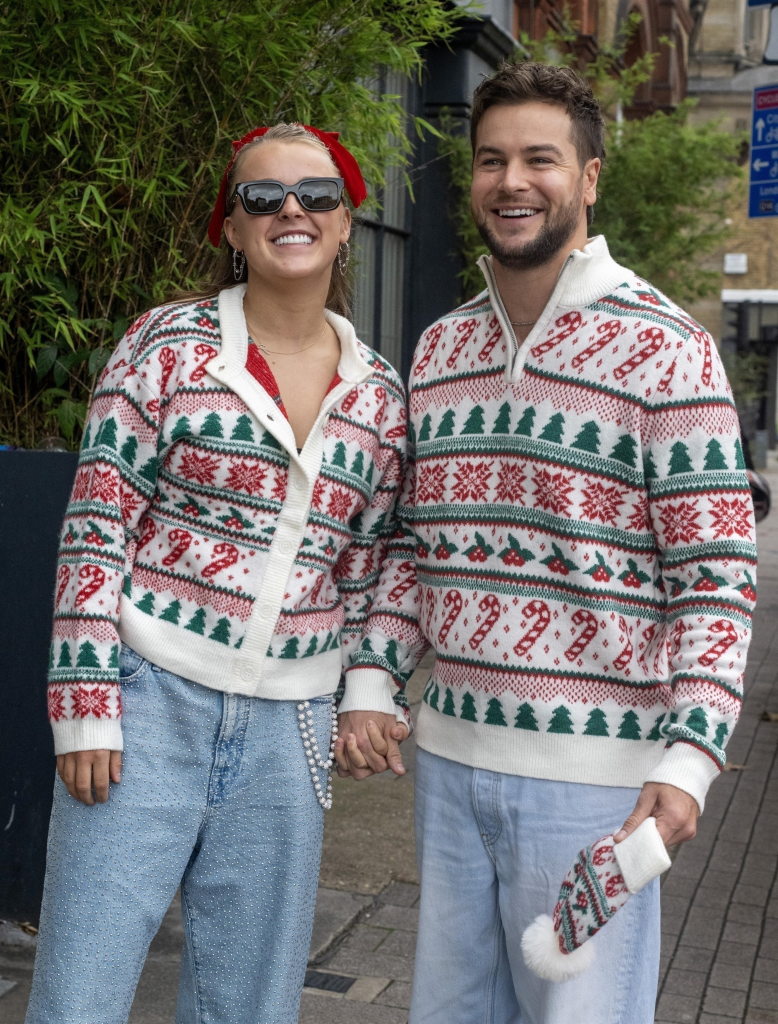 JoJo Siwa and Chris Hughes wearing matching Christmas-themed jumpers and holding hands.