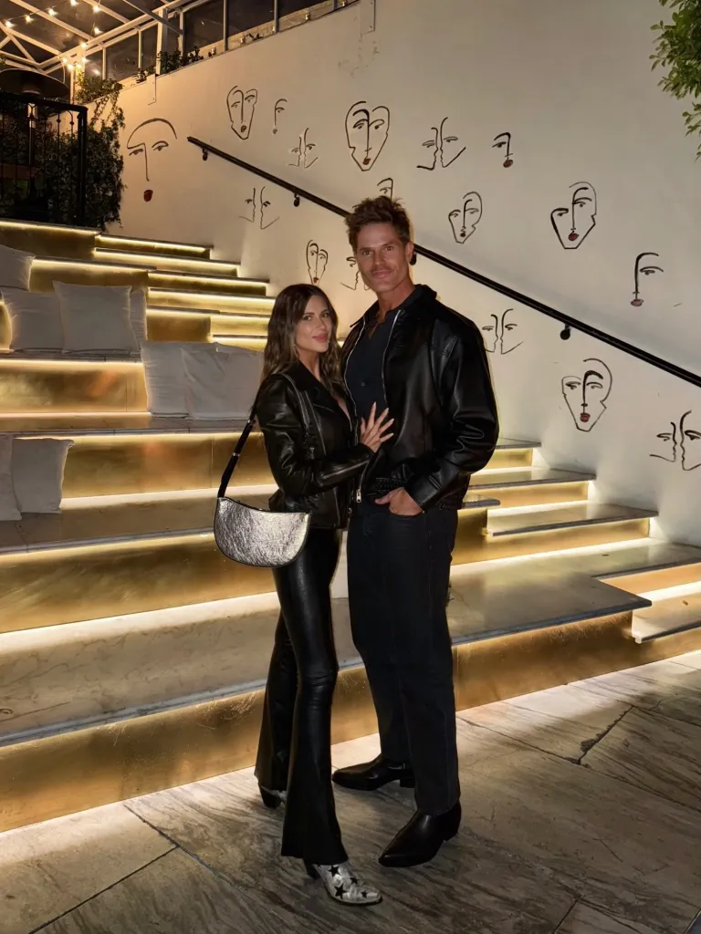 Demi Engemann and a man in a full black outfit standing in front of a staircase.