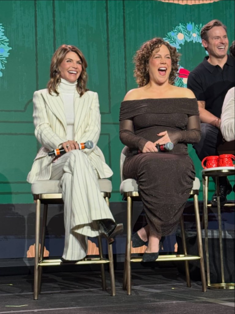 Lori Loughlin laughing while sitting with another woman on stage.