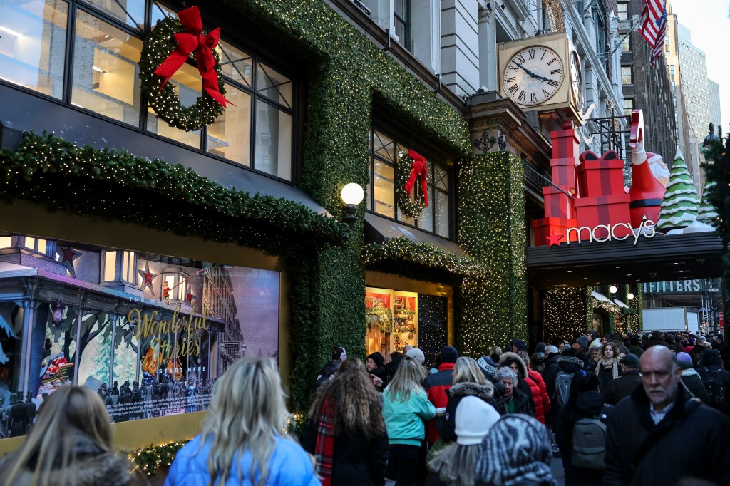 People walk in front of a Macy's department store decorated for Christmas.