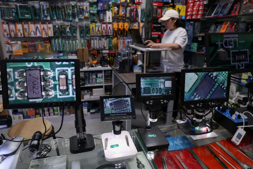 Magnifier screens showing chips at a booth in a Huaqiangbei electronics market.