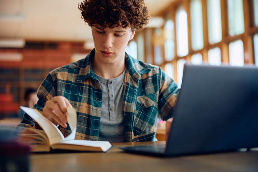 Male student learning at a high school library.