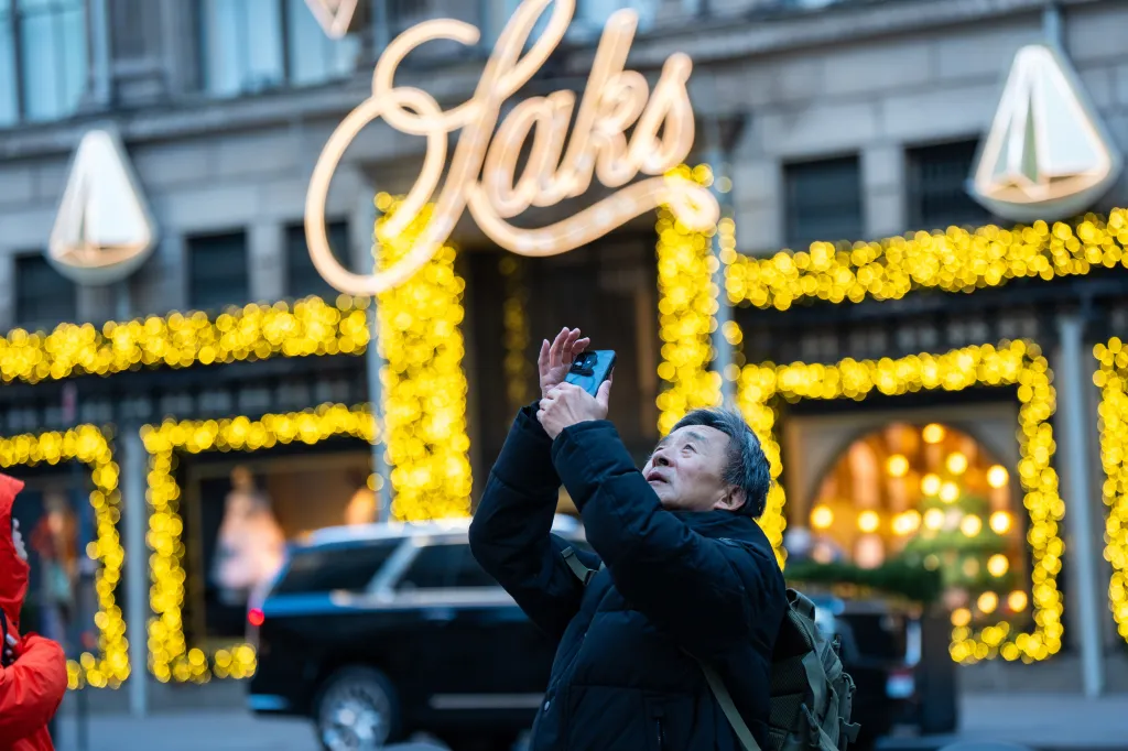 A man takes a photo of Rockefeller Center in front of Saks Fifth Avenue on Black Friday.