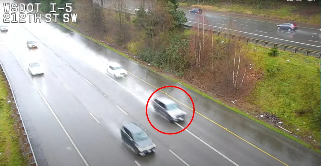 CCTV footage shows a car, circled in red, carjacking a Washington State Trooper's patrol car on a Seattle freeway.