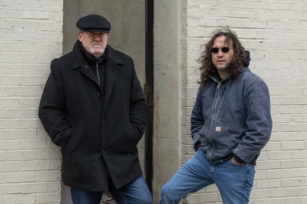 Retired Yonkers detective Mike Lorenzo (left) and Manny Grossman (right) standing in front of a light brick wall.
