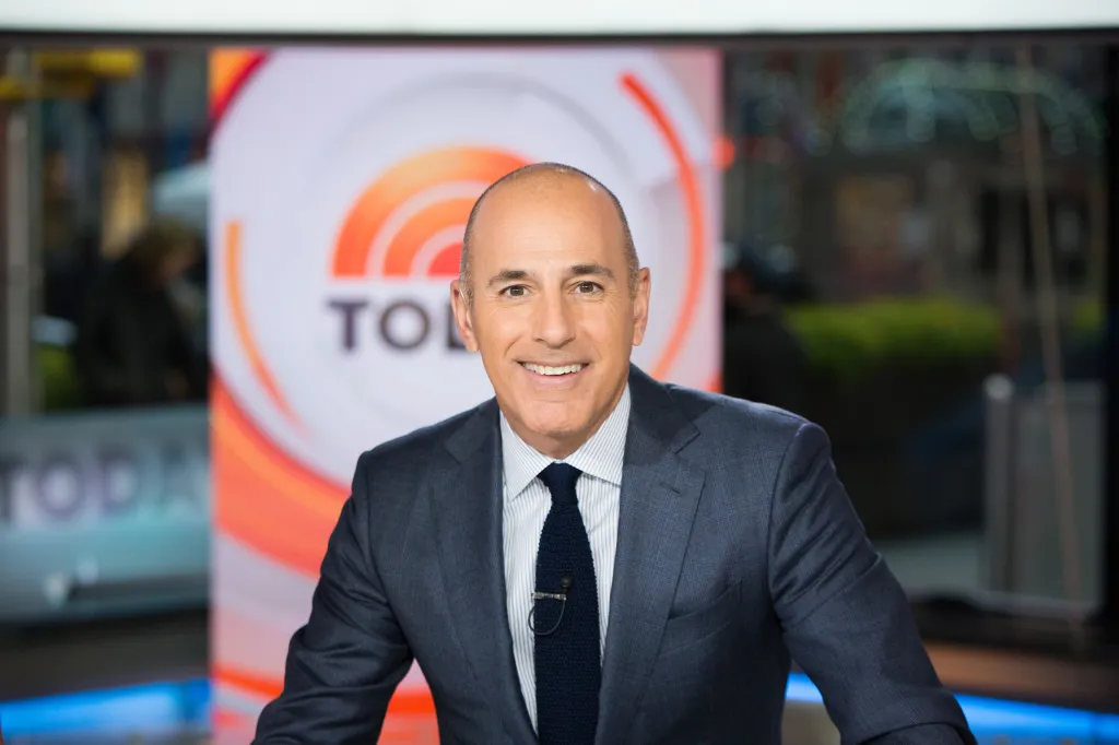 Matt Lauer smiling and looking at the camera in front of a screen displaying the Today show logo.