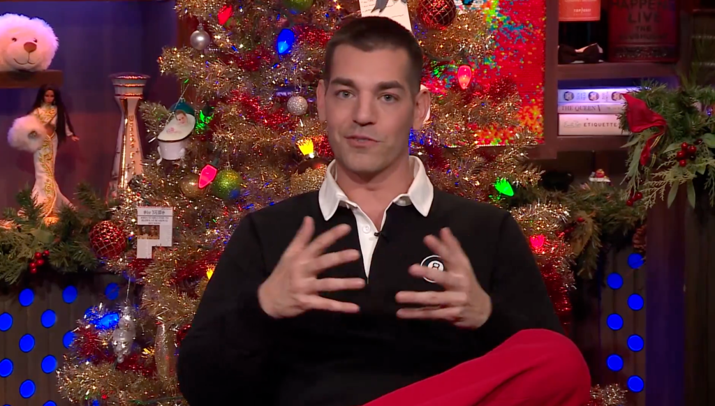 Matt Rogers talking in front of a decorated Christmas tree.