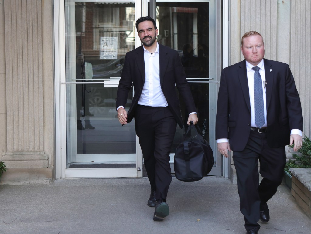 Mayor-elect Zohran Mamdani leaves his Astoria, NY residence, accompanied by a man in a suit.