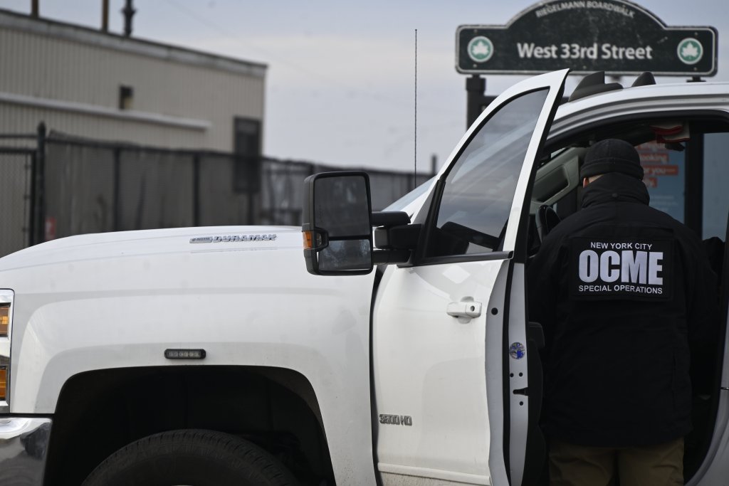 An NYC OCME Special Operations member in a black jacket and hat gets out of a white truck near a