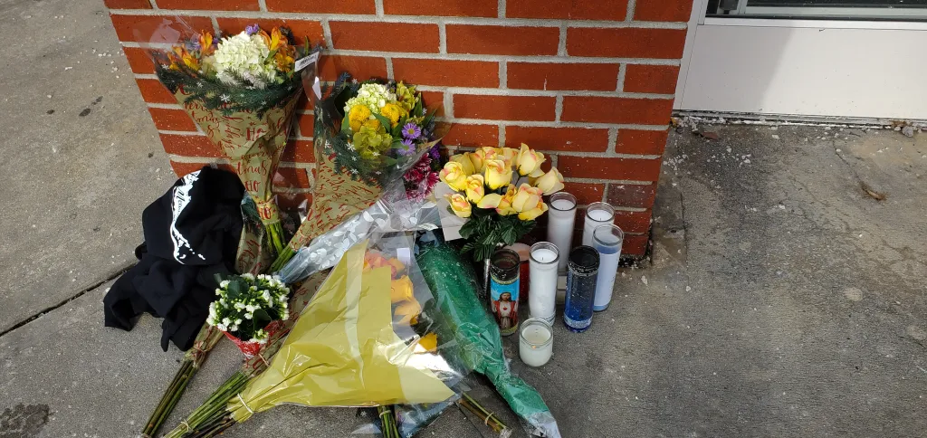 Memorial of flowers and candles for Edeedson Cine at a CVS store.