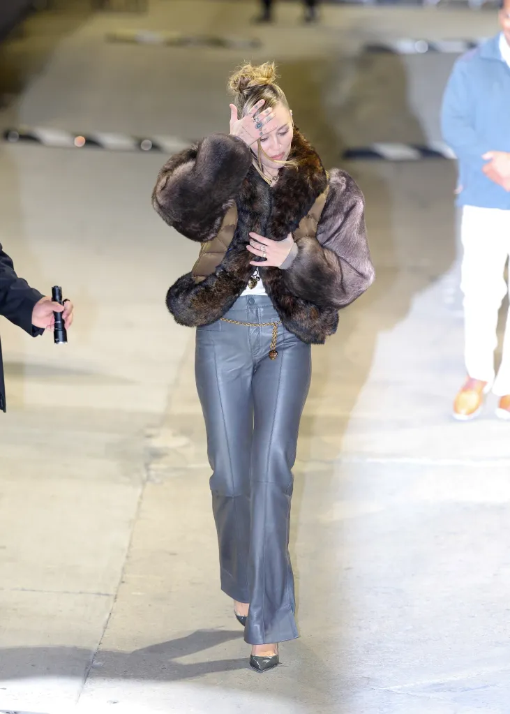 Miley Cyrus wearing a brown fur-trimmed jacket and gray leather pants.