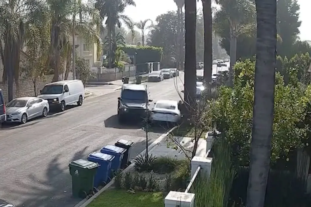 Surveillance footage of a dark SUV crashed into the back of a white car on a residential street.