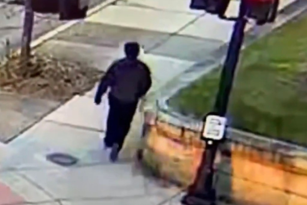 Security camera footage of a person walking on a sidewalk.