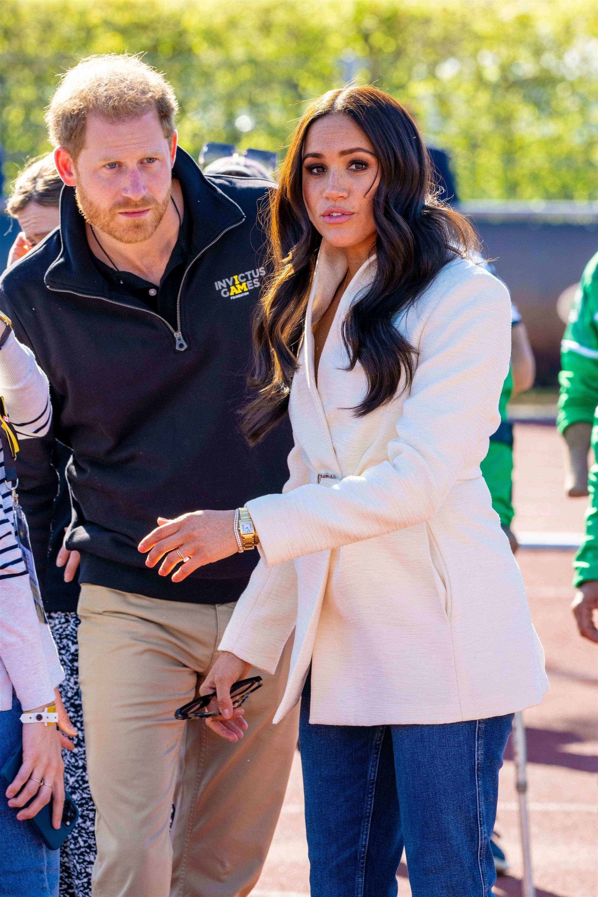 Prince Harry in an Invictus Games jacket and Meghan Markle in a white blazer.