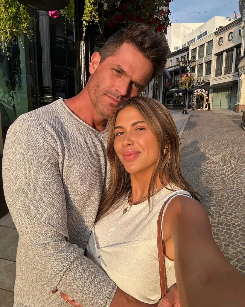 Demi Engemann and her husband Bret pose closely for a selfie on a cobblestone street.