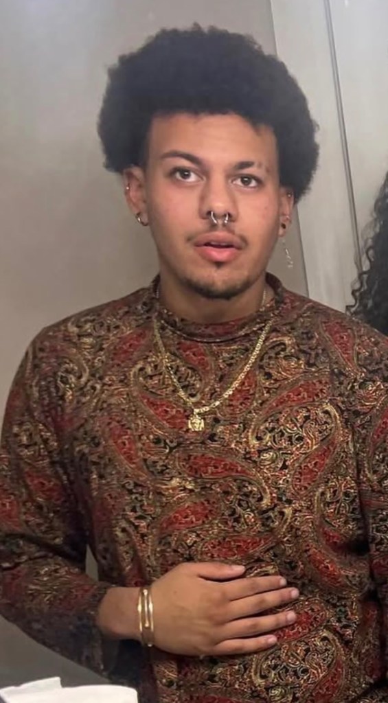 Morty Wortman wearing a paisley shirt, a gold chain, and several piercings.