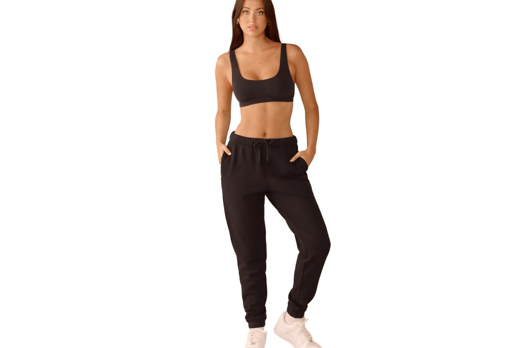 A woman wearing a black sports bra and black joggers.