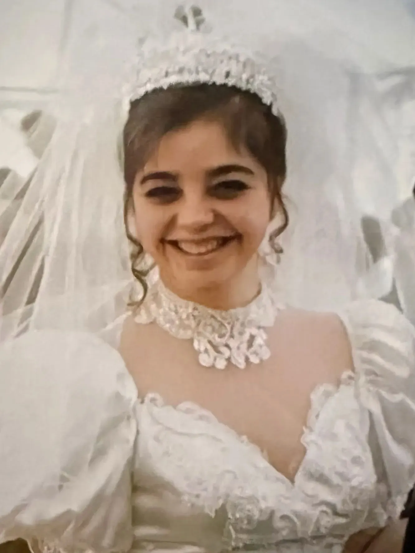 Adelia Ada Zeidler smiling in a white wedding gown with a veil and crown.