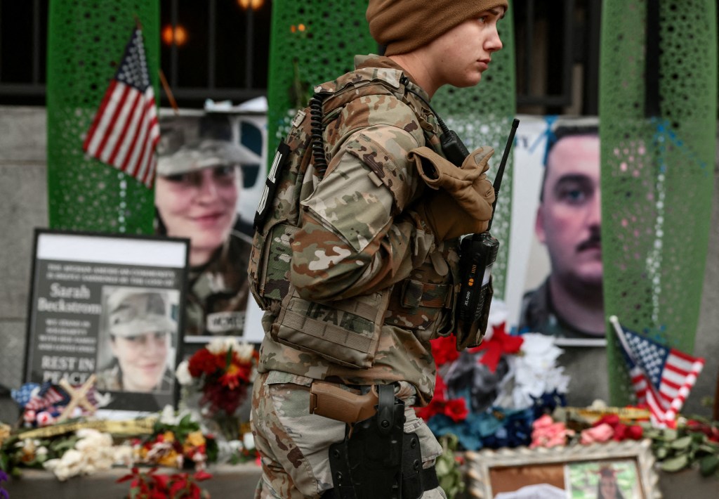 A National Guard soldier walks near a makeshift memorial honoring the two National Guard members shot near the White House.