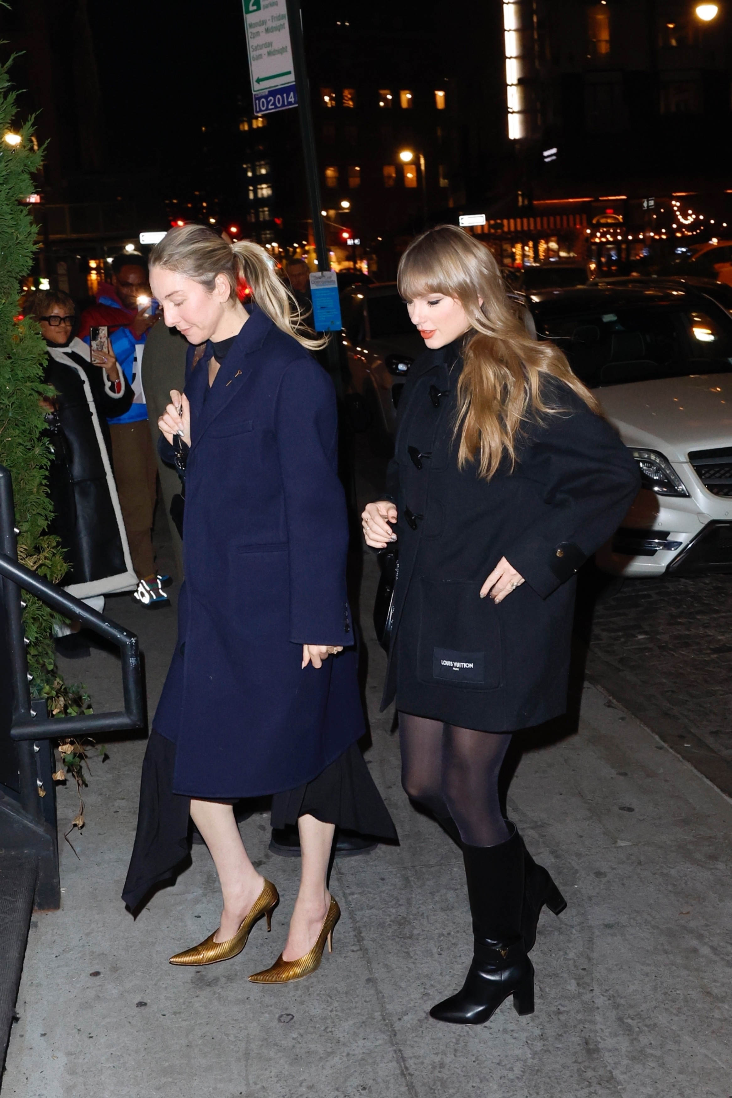 Taylor Swift and a friend walking at night for dinner at Chez Margaux in New York.