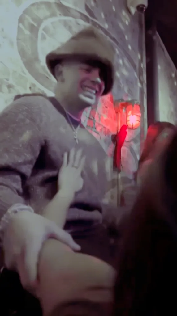 A man in a hat with a woman's hand on his chest.