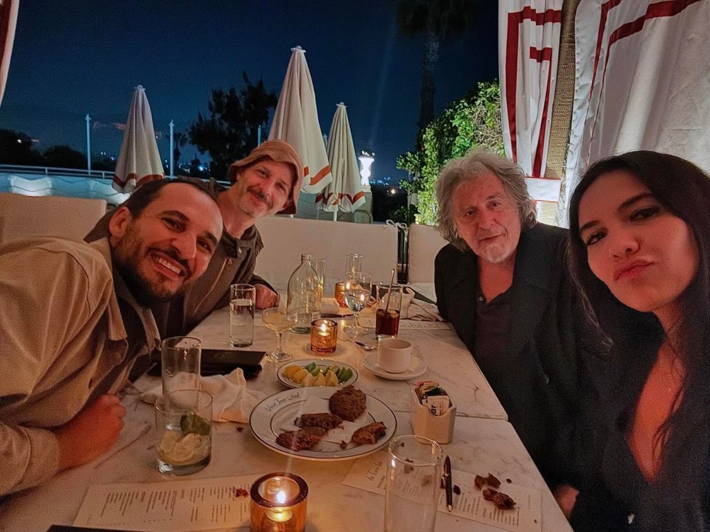 Noor Alfallah, Al Pacino, and two other people smiling at a dinner table.