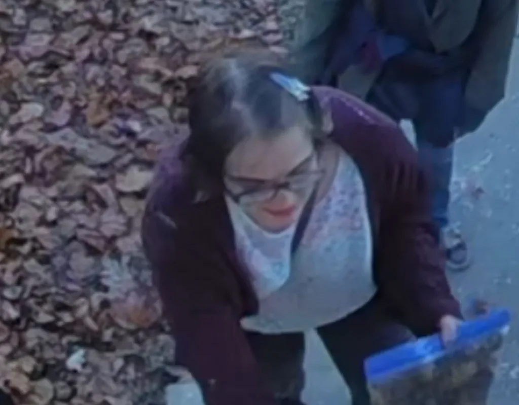 Morgan Geyser in glasses and a dark red cardigan, holding a clear plastic bag.
