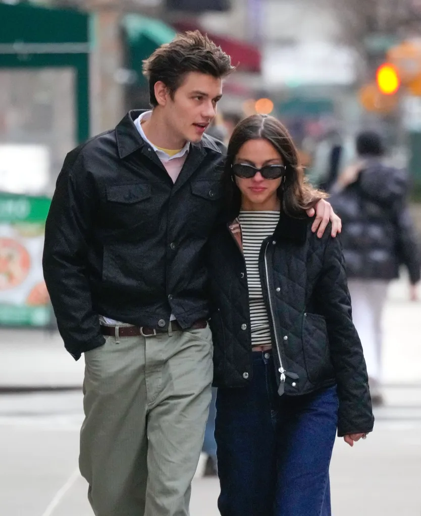 Olivia Rodrigo and Louis Partridge walking down a city street.