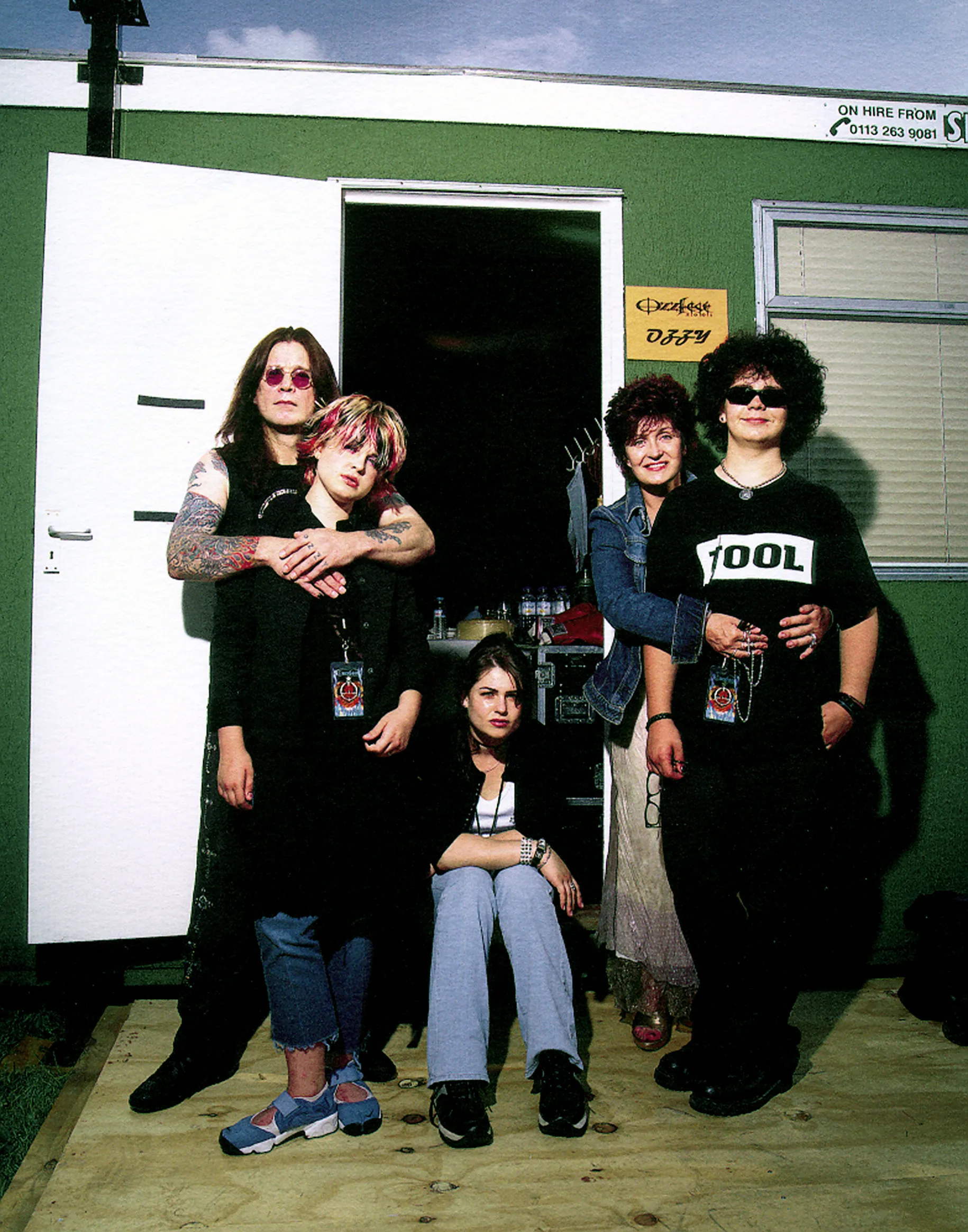 Ozzy, Kelly, Aimee, Sharon, and Jack Osbourne posing in front of a green trailer.