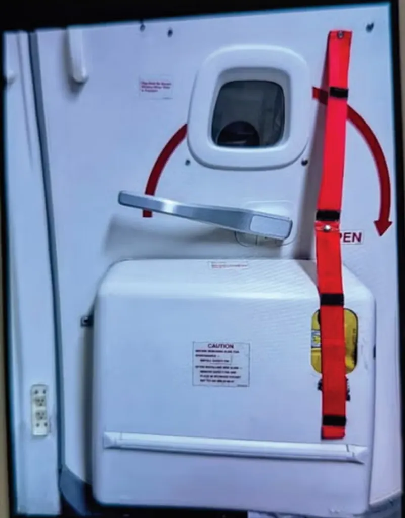 An open airplane door with a red emergency slide strap.
