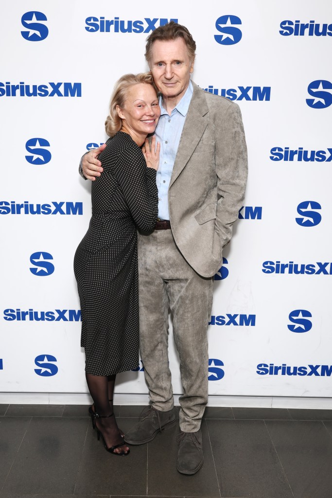 Pamela Anderson and Liam Neeson embracing at SiriusXM Studios.