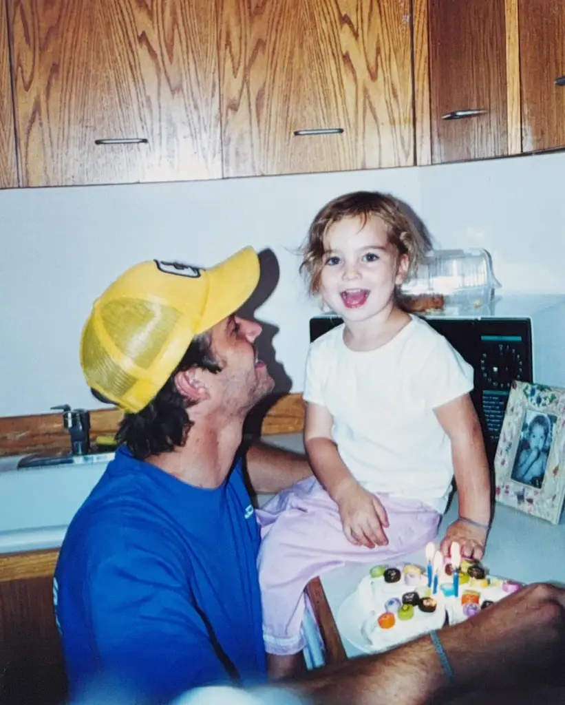 Paul Walker looking up at his daughter Meadow as she sits on a counter next to a birthday cake.