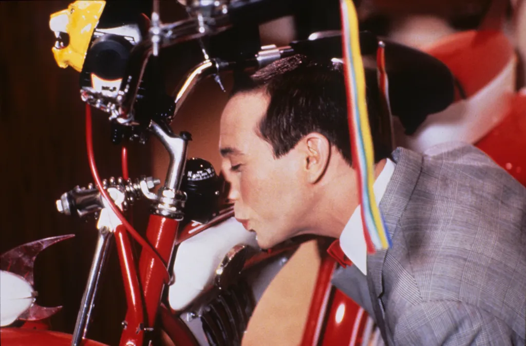 Pee-wee Herman kissing his bicycle.