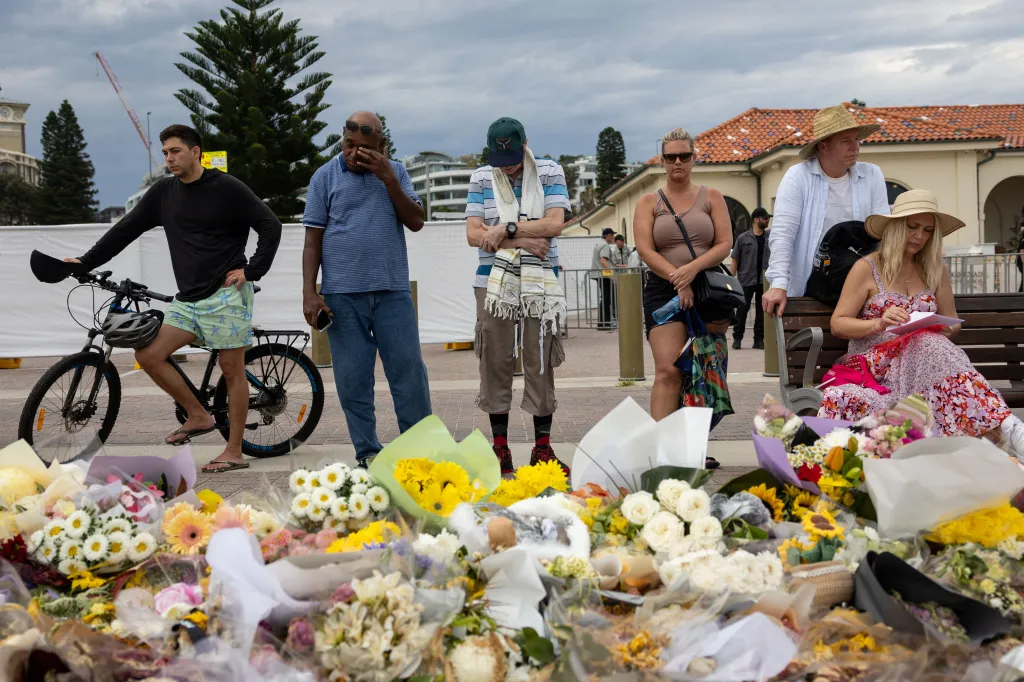 People mourn near floral tributes for victims and survivors of a deadly mass shooting in Sydney, Australia.