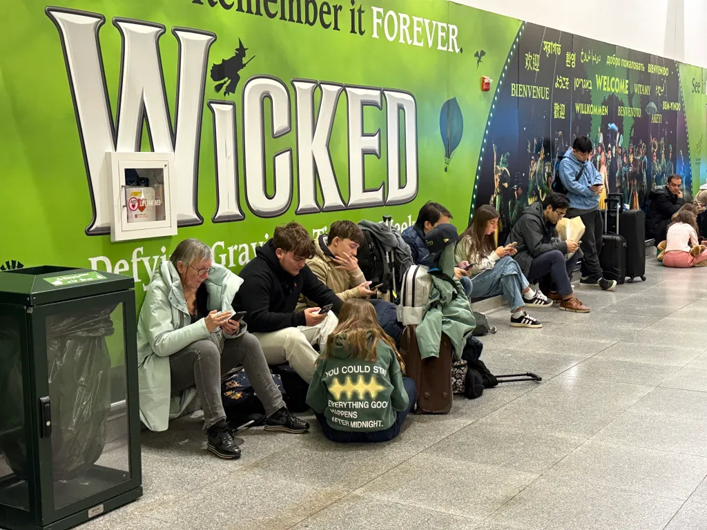 Travelers sit on the floor of John F. Kennedy International Airport, waiting for flights.