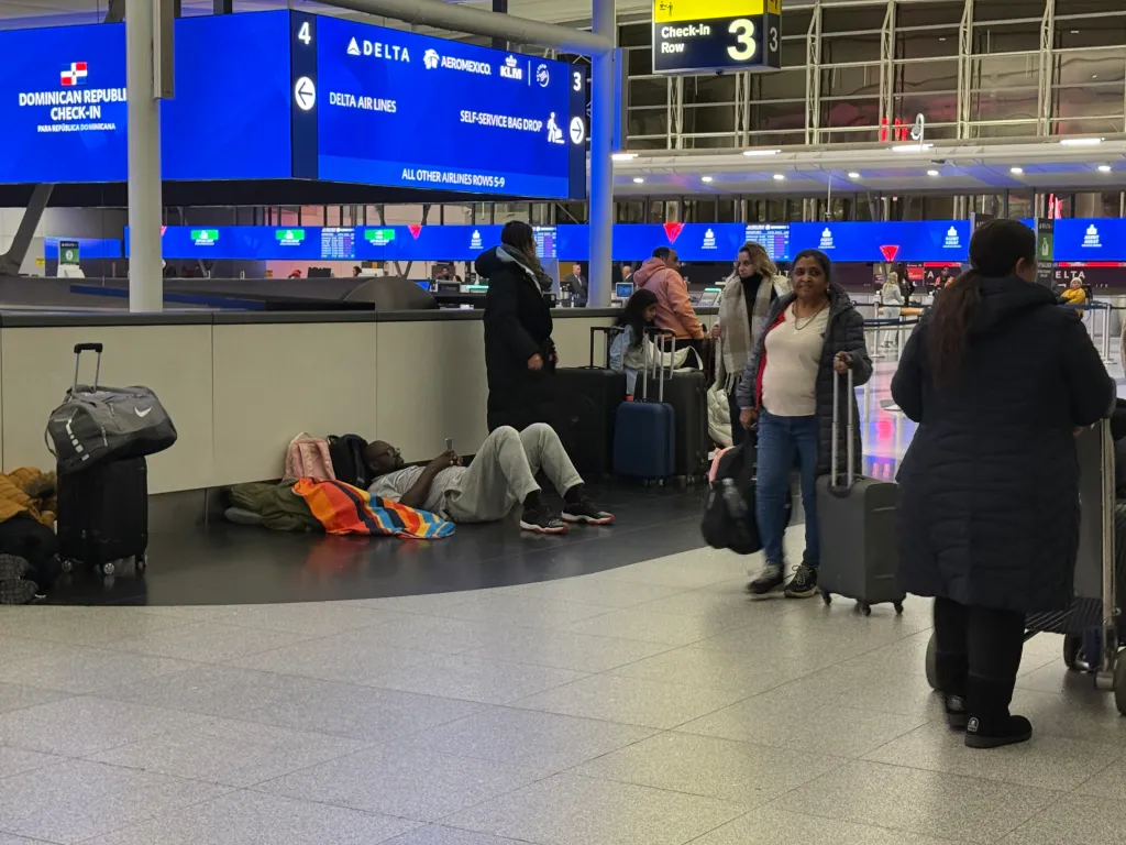 People are seen getting to gates and sitting around in Terminal 4 at John F. Kennedy International Airport as a snowstorm causes flight cancellations.