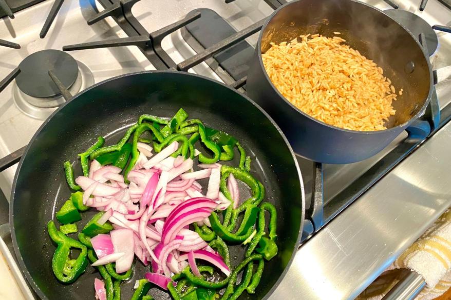 A pan filled with peppers and rice cooking on a stove