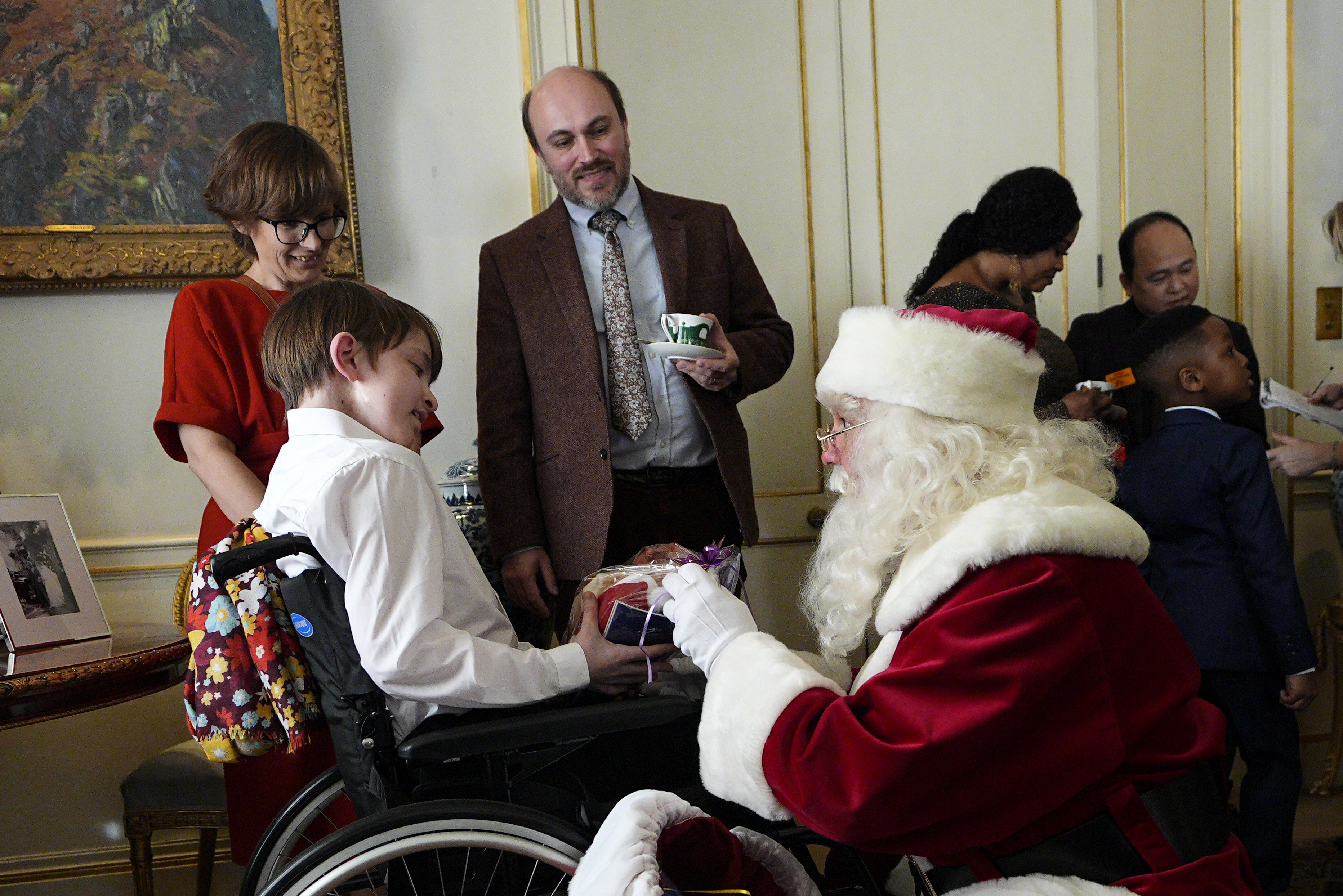 Father Christmas giving a gift to a boy in a wheelchair at Clarence House.