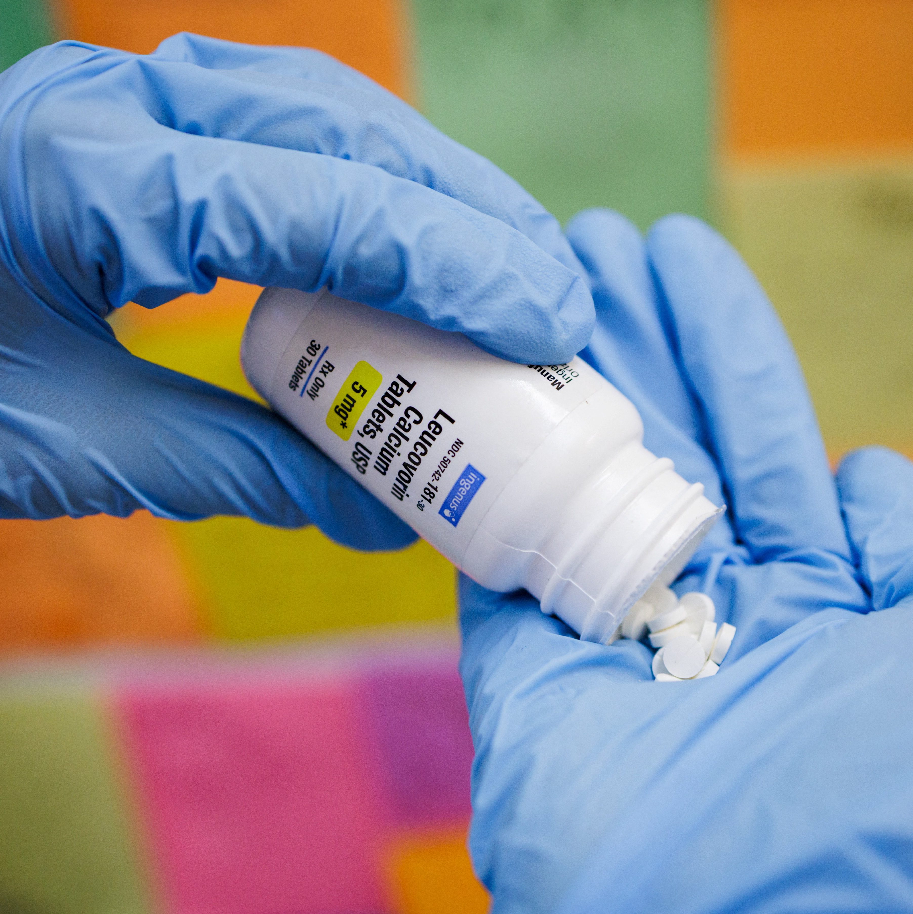 Illustration of gloved hands holding a bottle of Leucovorin tablets, with some tablets spilled into a hand.