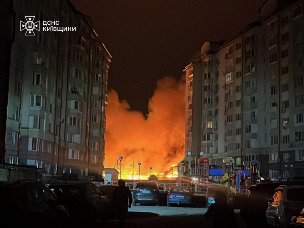 Fire and smoke rise behind apartment buildings near Kyiv after an overnight strike.