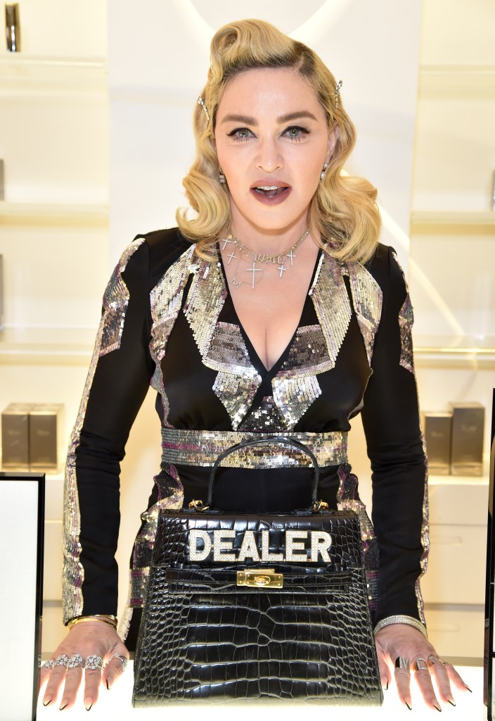 Madonna posing with a black crocodile-embossed handbag featuring the word
