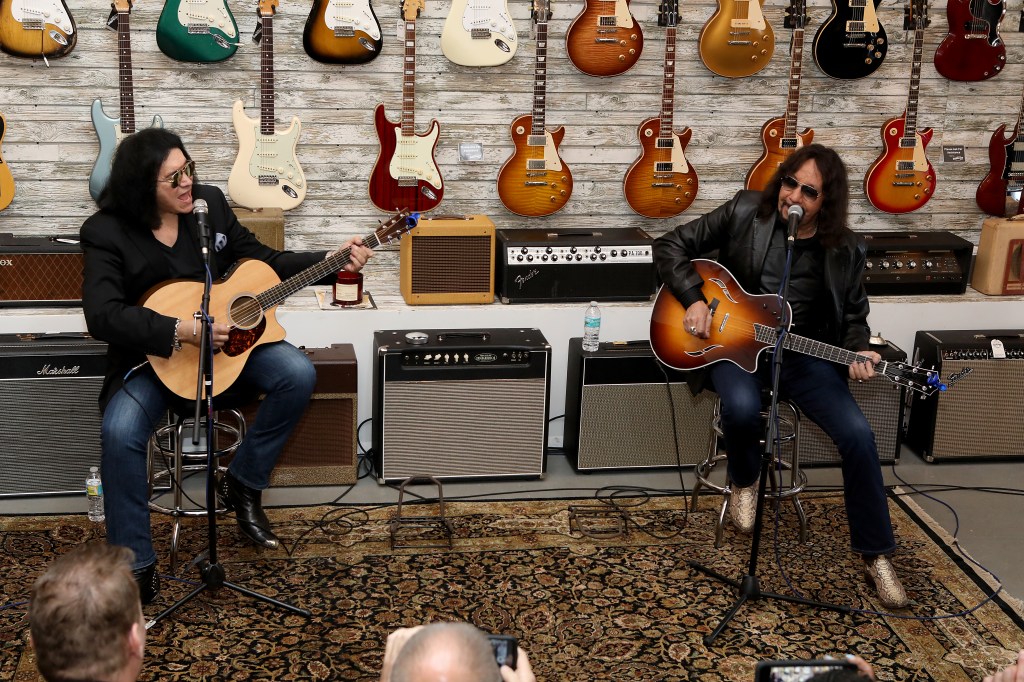 Gene Simmons and Ace Frehley performing live with acoustic guitars.