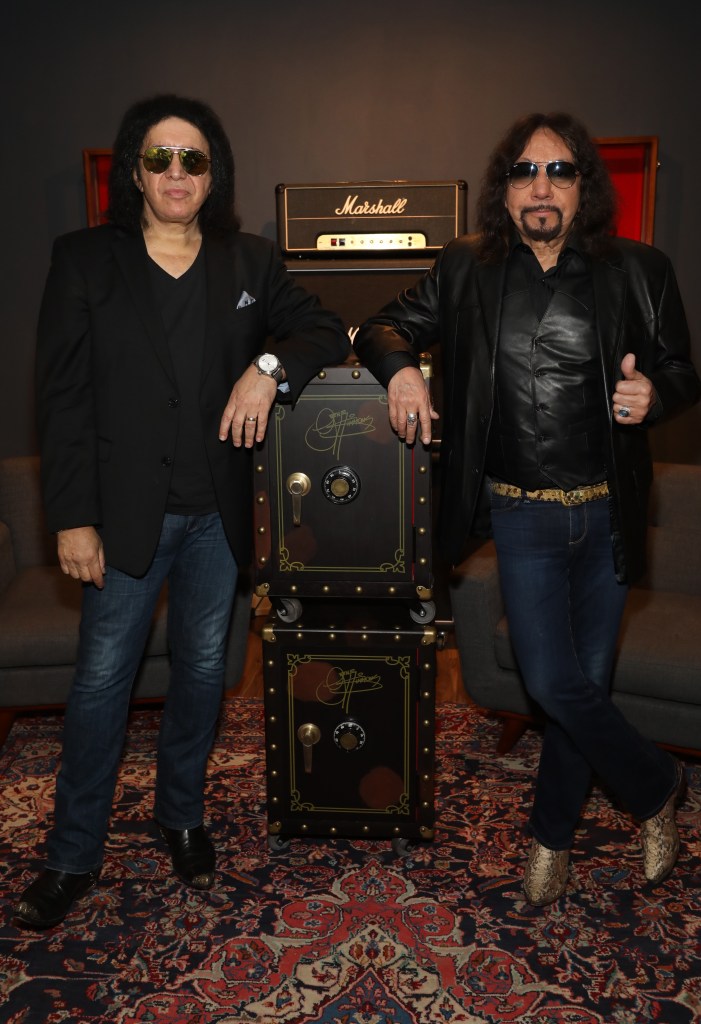 Musicians Gene Simmons and Ace Frehley standing next to each other, leaning on black safes.