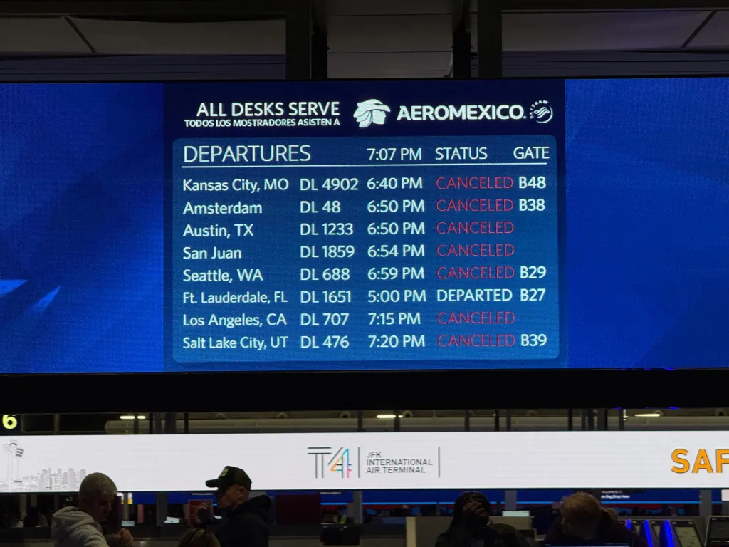 Electronic screen in Terminal 4 at JFK Airport showing multiple canceled Aeromexico flights.