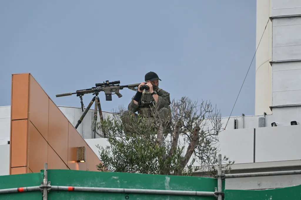 A sniper is stationed on the roof of a building overlooking the memorial held for the victims of the Bondi Beach shooting.