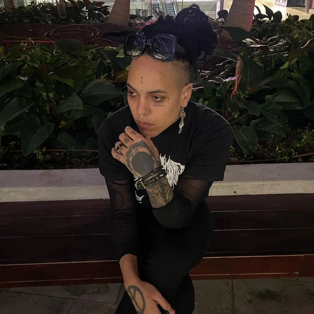 Poorstacy sitting on a bench with plants in the background.