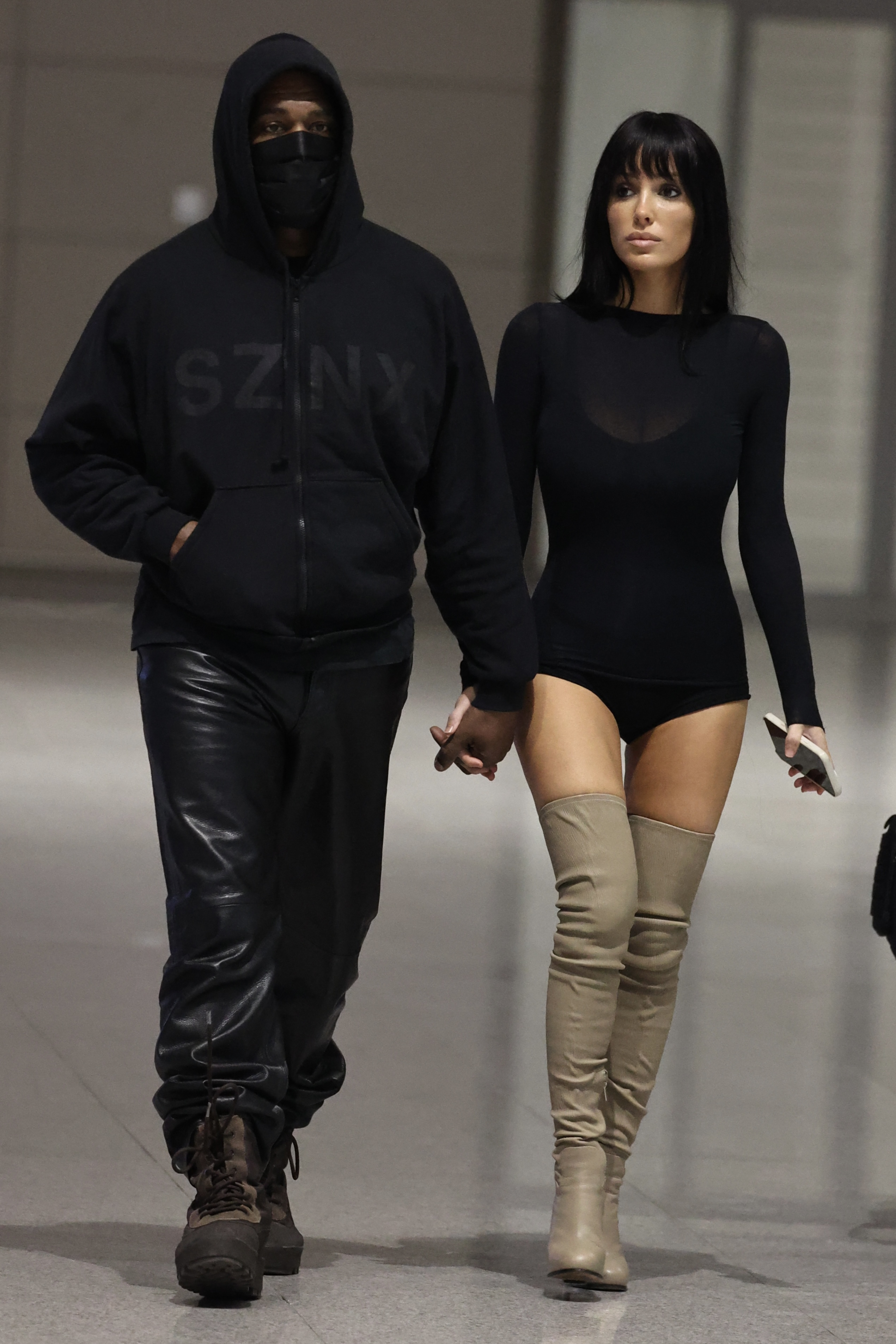 Kanye West and Bianca Censori holding hands at Seoul Airport.