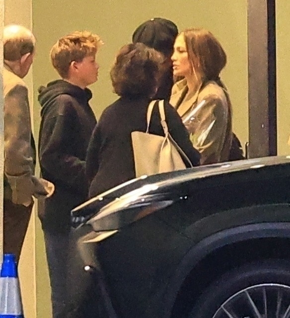 Jennifer Lopez in a tan top standing next to Samuel Affleck and a woman wearing a black jacket and carrying a light-colored tote bag.