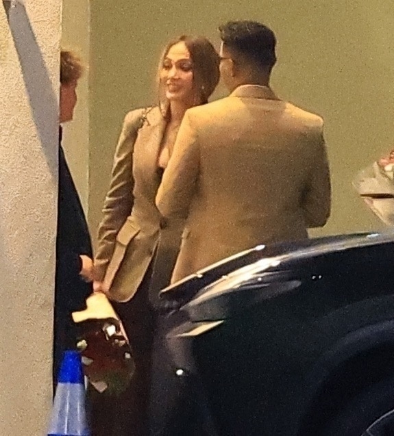 Jennifer Lopez, in a brown blazer, smiling while talking to Samuel Affleck